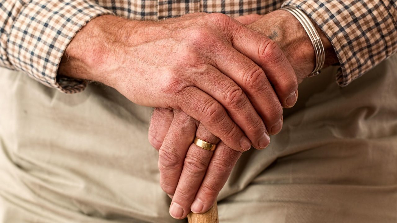 Les mains d'un homme âgé qui tient une canne de marche