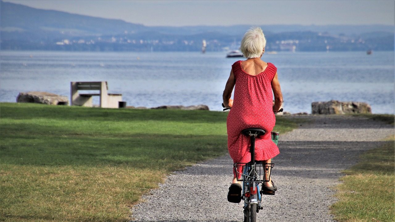 Une femme âgée en robe rouge qui fait du vélo
