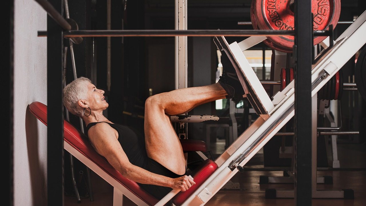 Femme senior à la salle de sport sur un banc de musculation