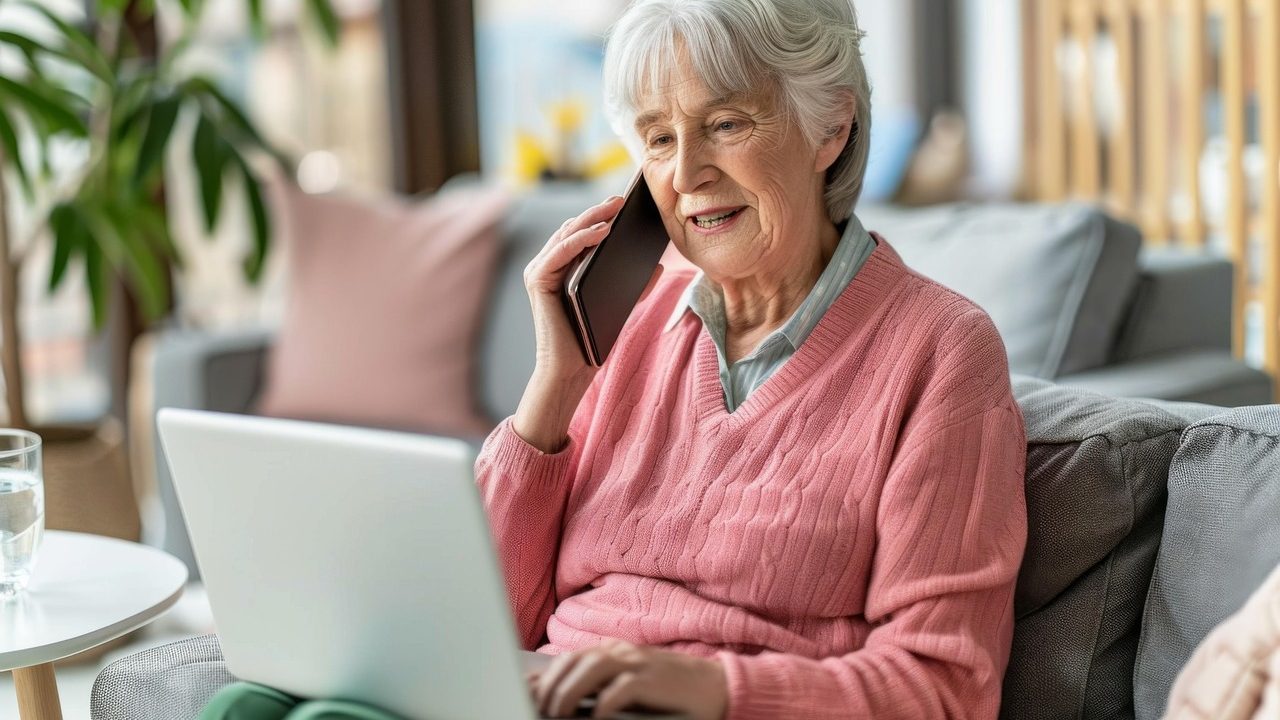 Femme senior au téléphone devant son ordinateur portable