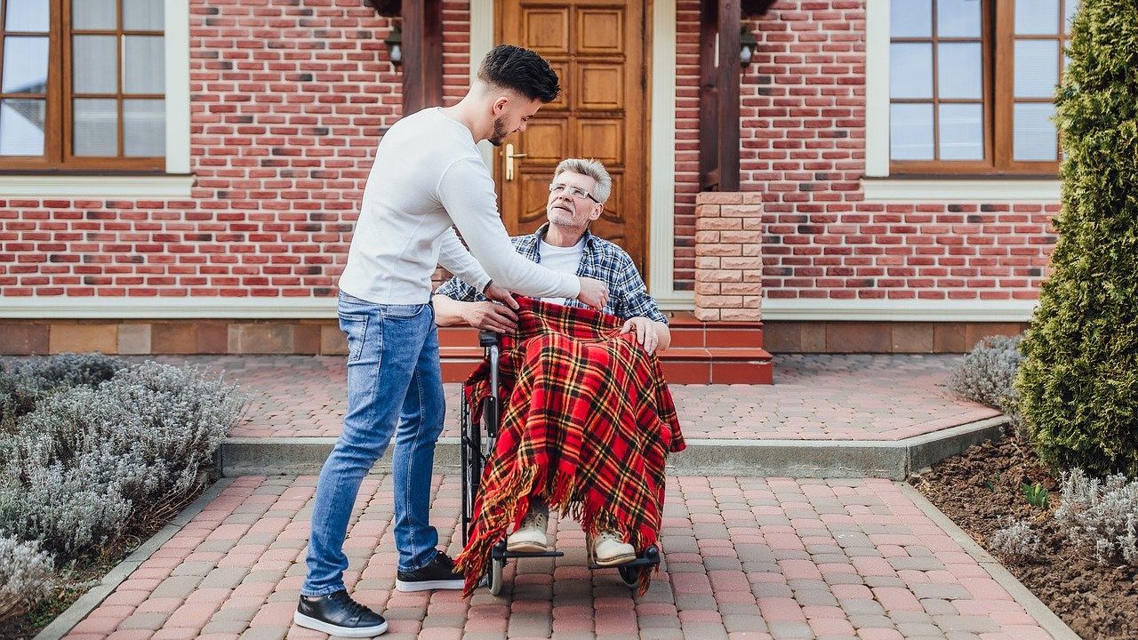 Un jeune homme qui aide un senior en fauteul roulant
