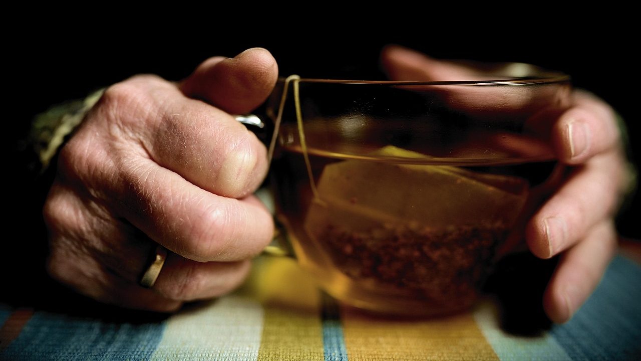 Les mains d'une personne âgée qui tiennent une tasse de tisane
