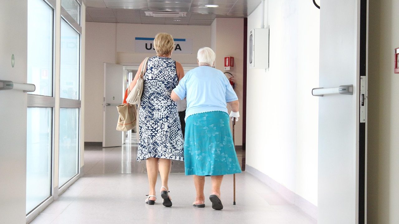 Une femme âgée qui se déplace dans un couloir d'hôpital au bras de sa fille